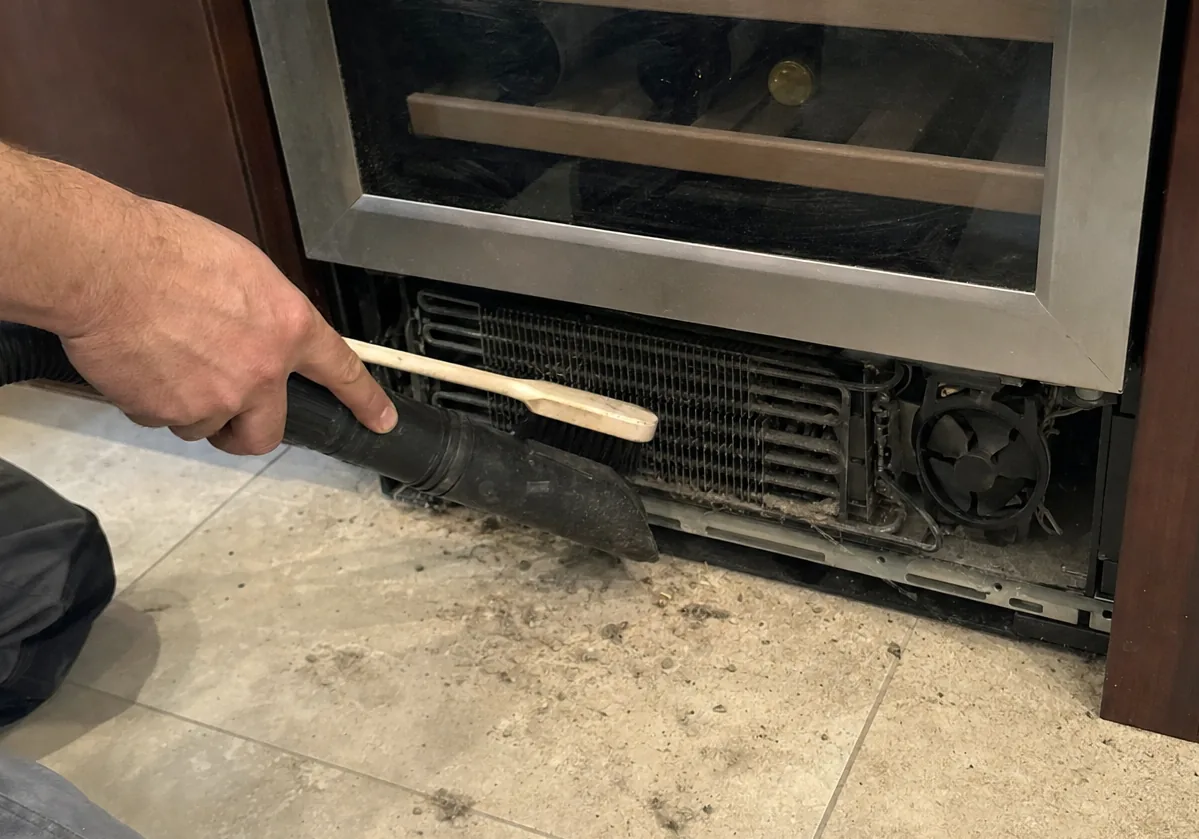 Centred frame of a vacuum hose at the open base of a refrigeration cabinet, grille removed